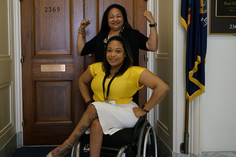 Image of a woman in wheelchair and woman behind her flexing her arms